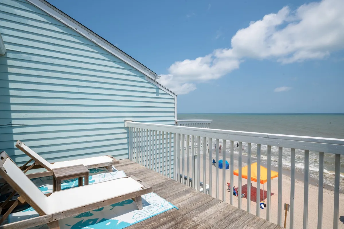 An inviting outdoor scene showing beach chairs and colorful umbrellas set up on the sand, all facing the ocean. The tranquil mood and wide ocean vista convey relaxation and the allure of beachside exploration.