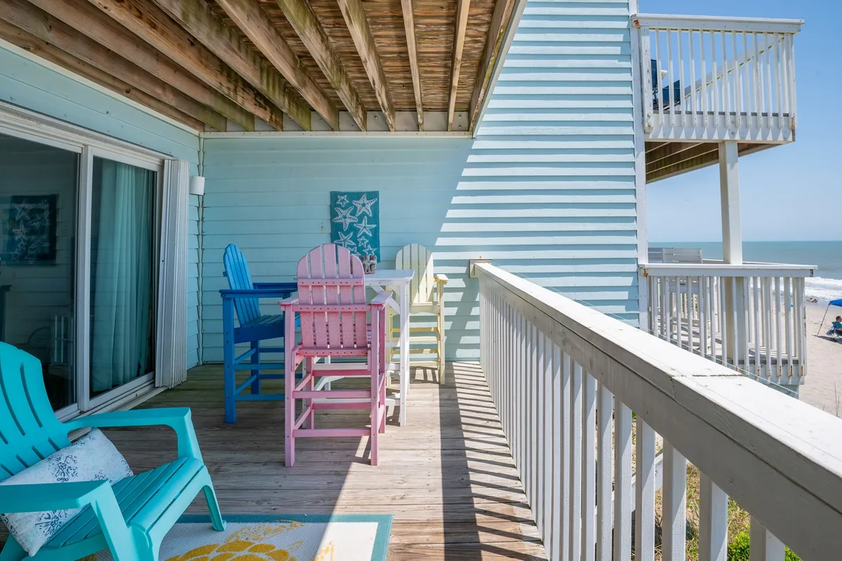 A private sun deck with colorful outdoor chairs, a panoramic beach view, and deck railing—a perfect spot for sipping morning coffee, reading, or simply soaking in the ocean atmosphere.