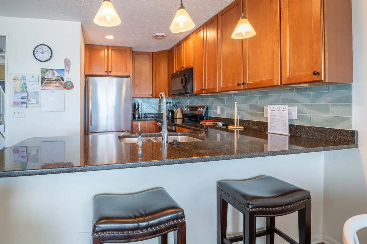This image showcases a kitchen featuring a prominent granite countertop, warm wooden cabinets, and a well-lit kitchen island. The space exudes a cozy, inviting ambiance, perfect for cooking and entertaining guests. The layout highlights ample workspace ideal for meal preparation.