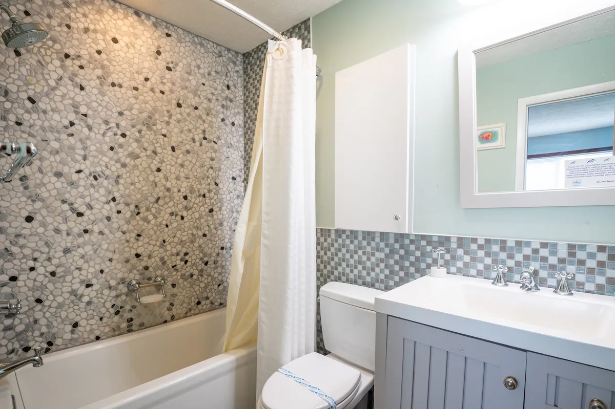 A modern bathroom with a spacious shower area, textured wall tiles, and a stylish vanity with sink. The fresh and inviting atmosphere makes it ideal for unwinding and daily rituals.